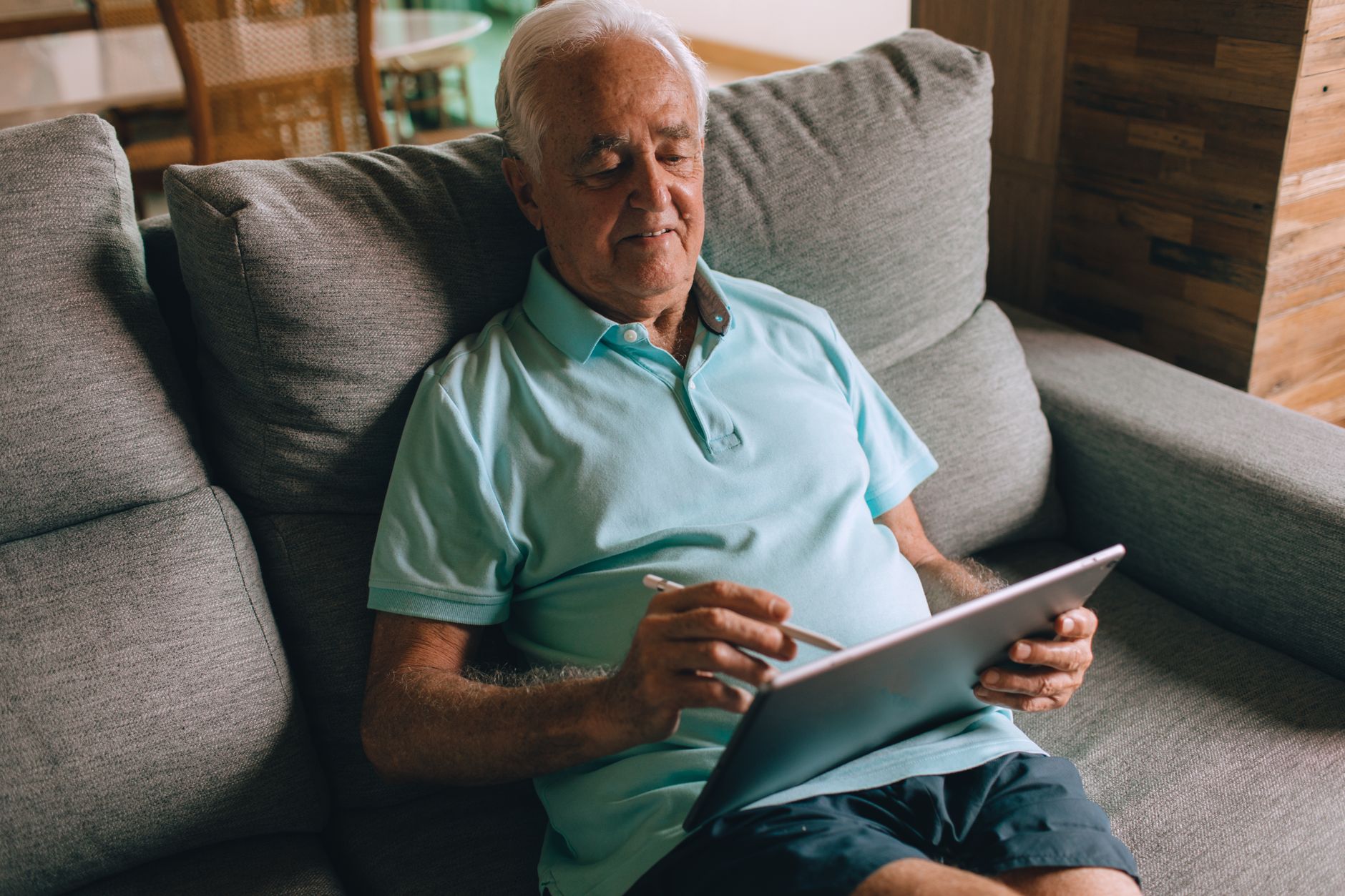 Man sitting on a couch reviewing campaign plans on a tablet.