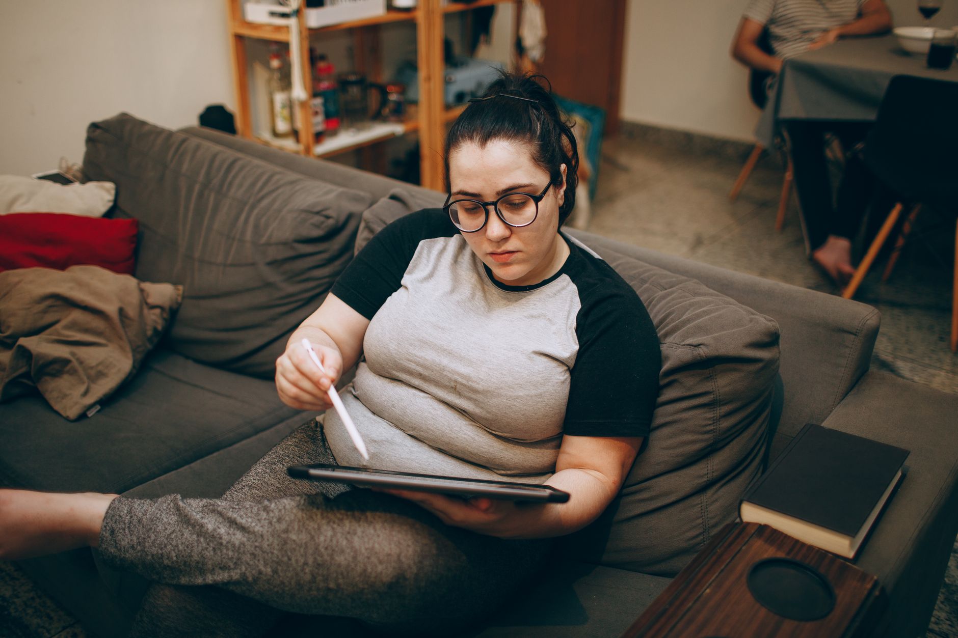Woman relaxing on a couch with a tablet, reviewing creative and landing pages.